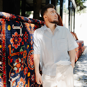 Man photographed beside a traditional carpet in Baku Old Town